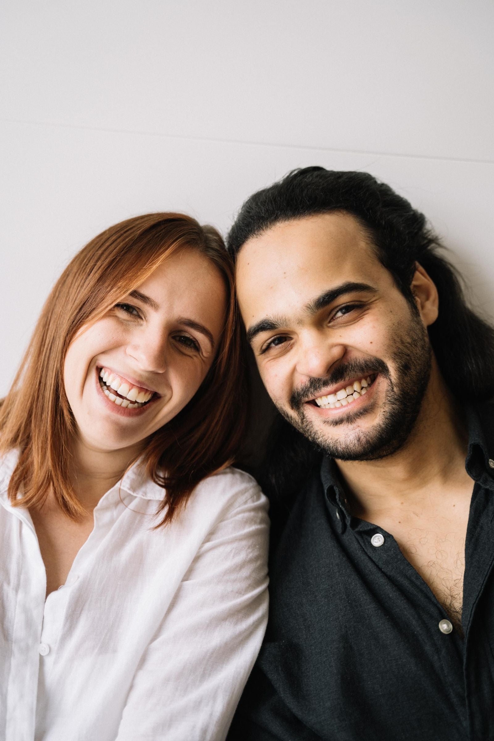 A couple standing close together and smiling toward the camera.